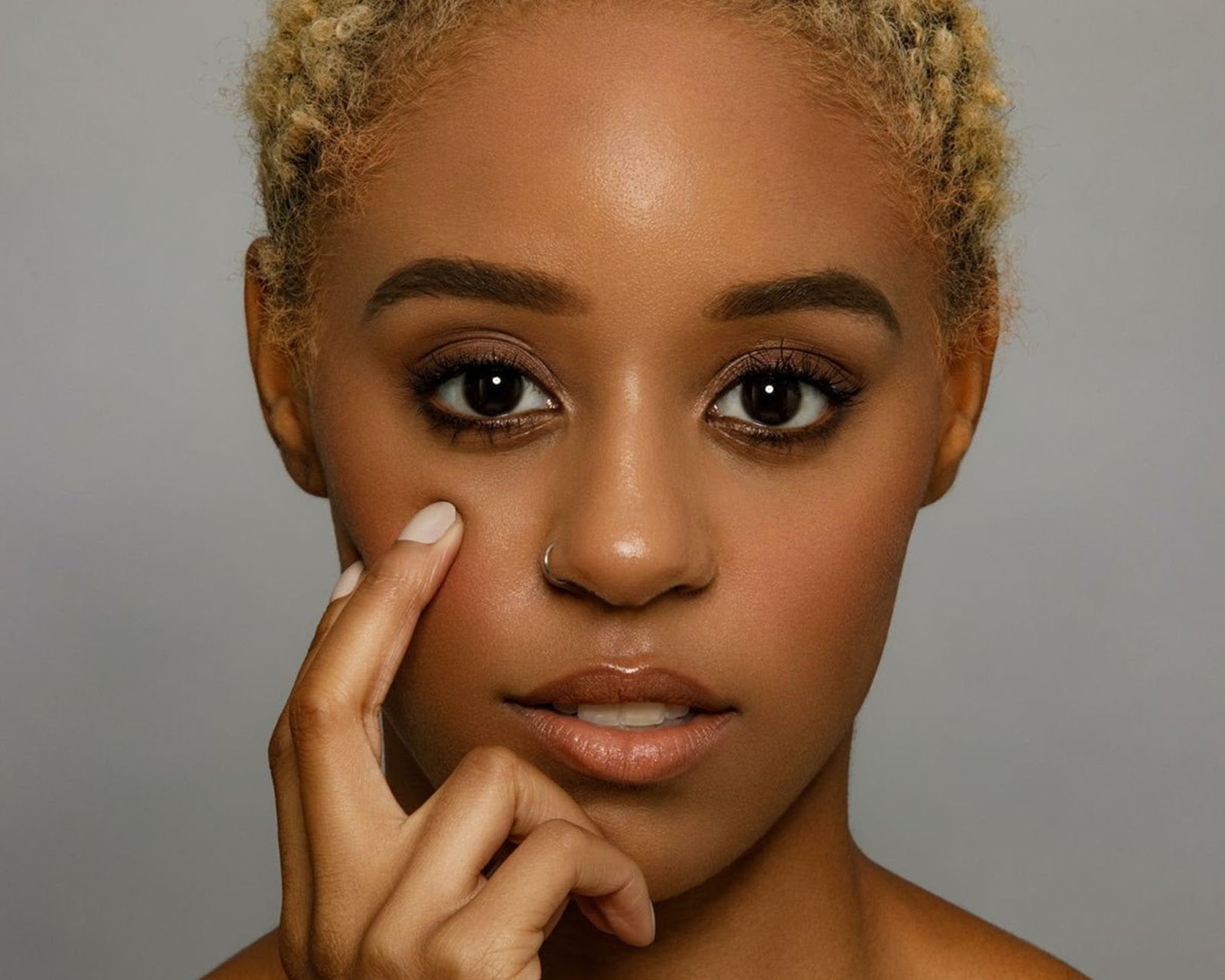 Closeup of a pretty, young Afro-american woman touching her face with fingertips