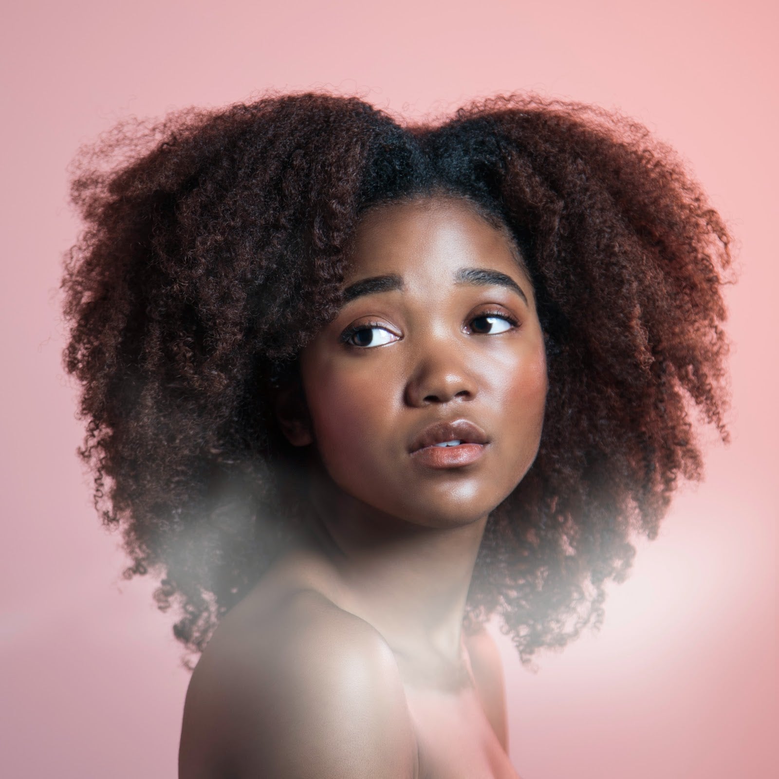 Pretty Afro-american girl with a twist out hairstyle isolated on the pink background