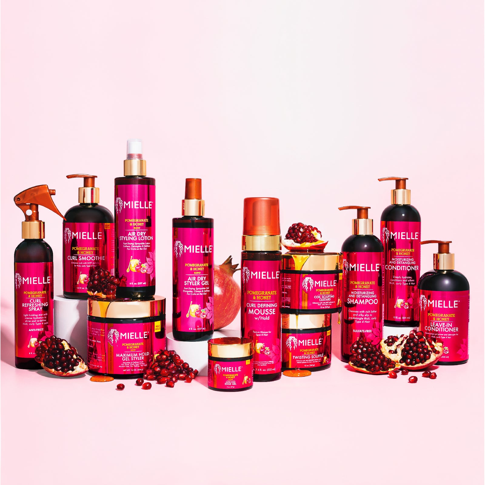 Various Mielle Organics hair care products displayed on a pink background.