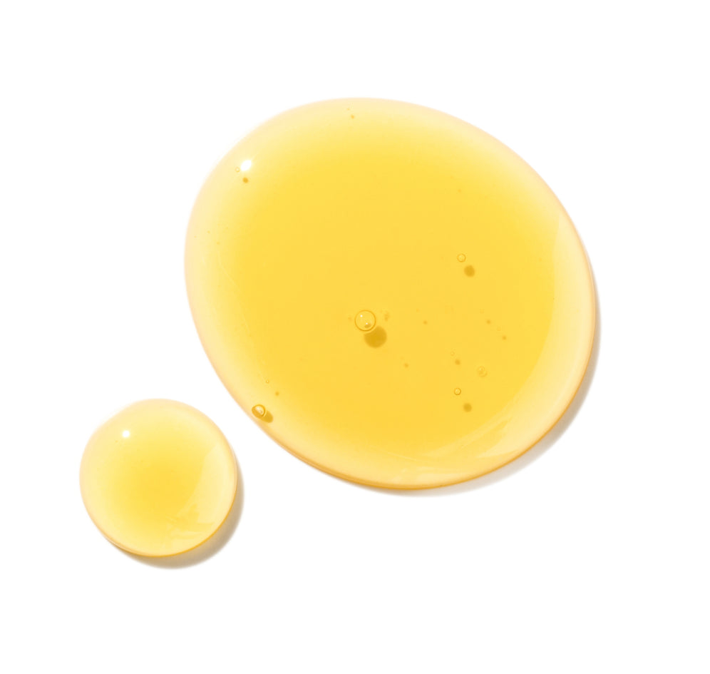 Yellow liquid drops, showcasing Mielle Organics hair care product texture.