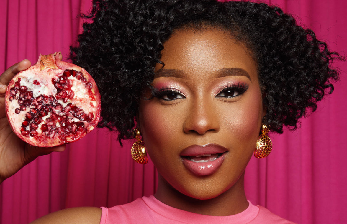 Woman with curly hair holding a pomegranate, promoting natural hair care.