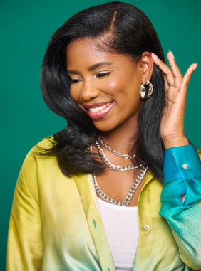 Woman smiling and touching her hair, showcasing Mielle Organics products.
