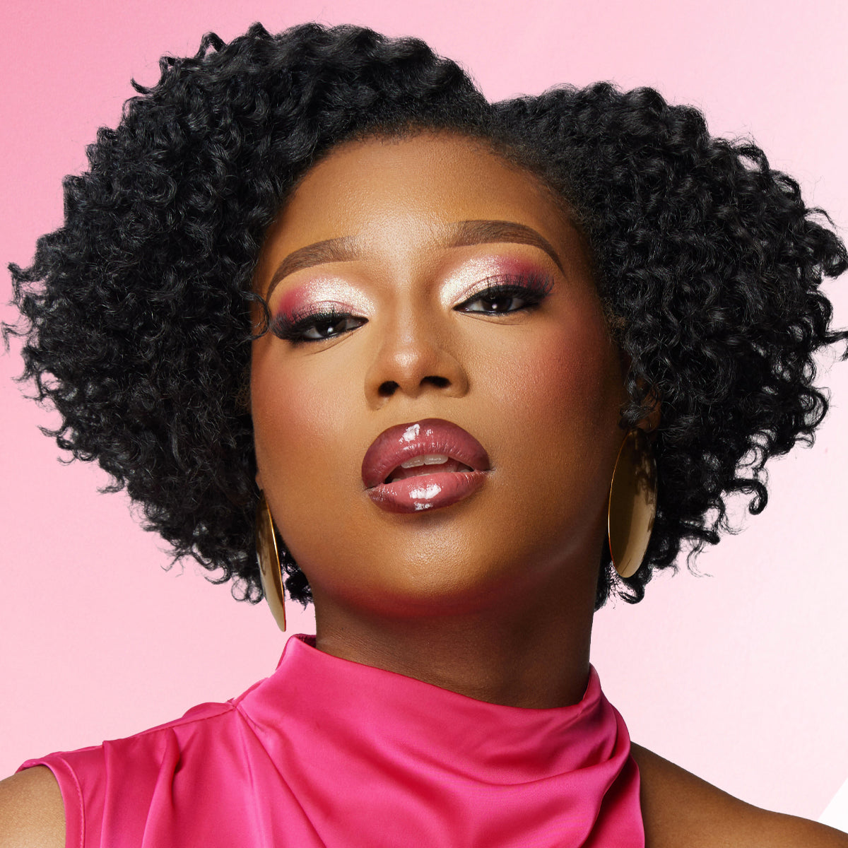 Woman with styled hair and pink makeup against a pink background