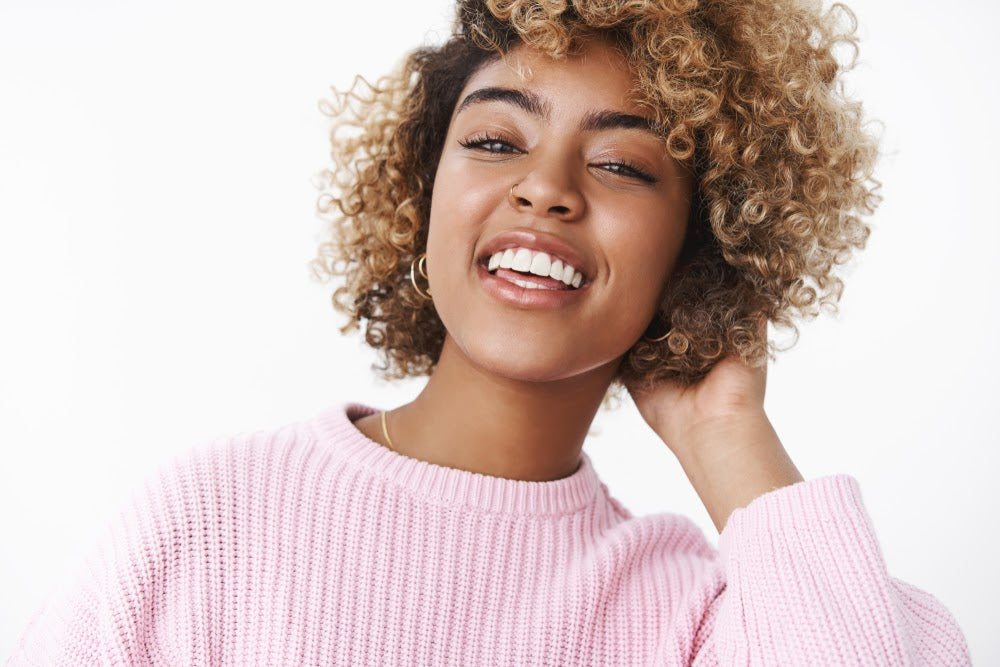 Stylish modern african-american girlfriend looking joyful and delighted at camera raising head proudly and smiling, laughing out loud touching curls on back