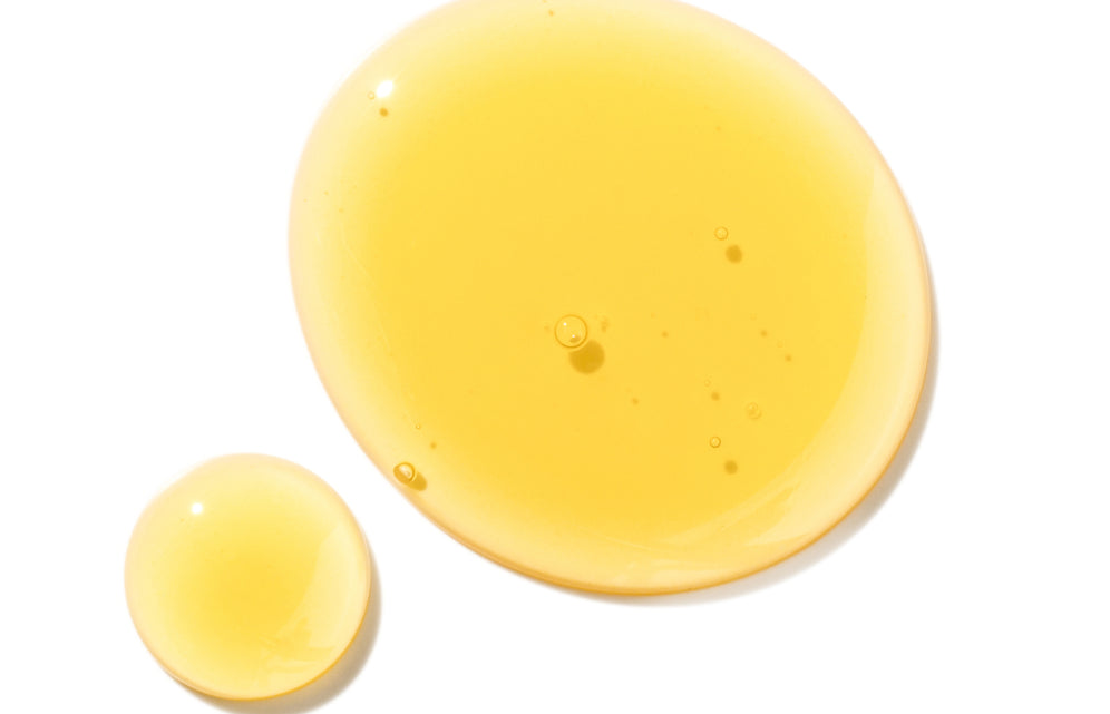Yellow liquid drops, showcasing Mielle Organics hair care product texture.